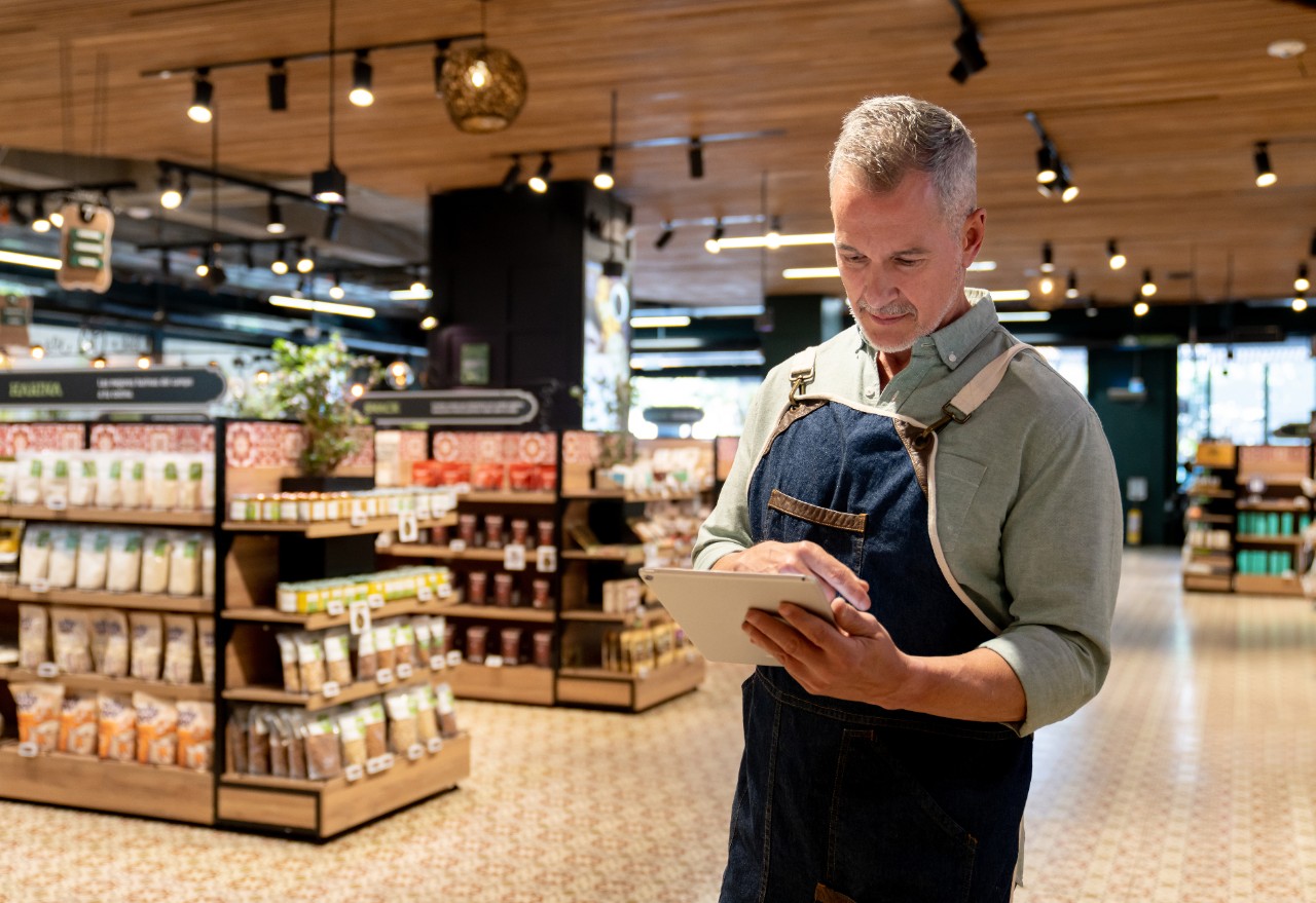 1562969078 Portrait of a Latin American retail clerk working at the supermarket using a digital tablet